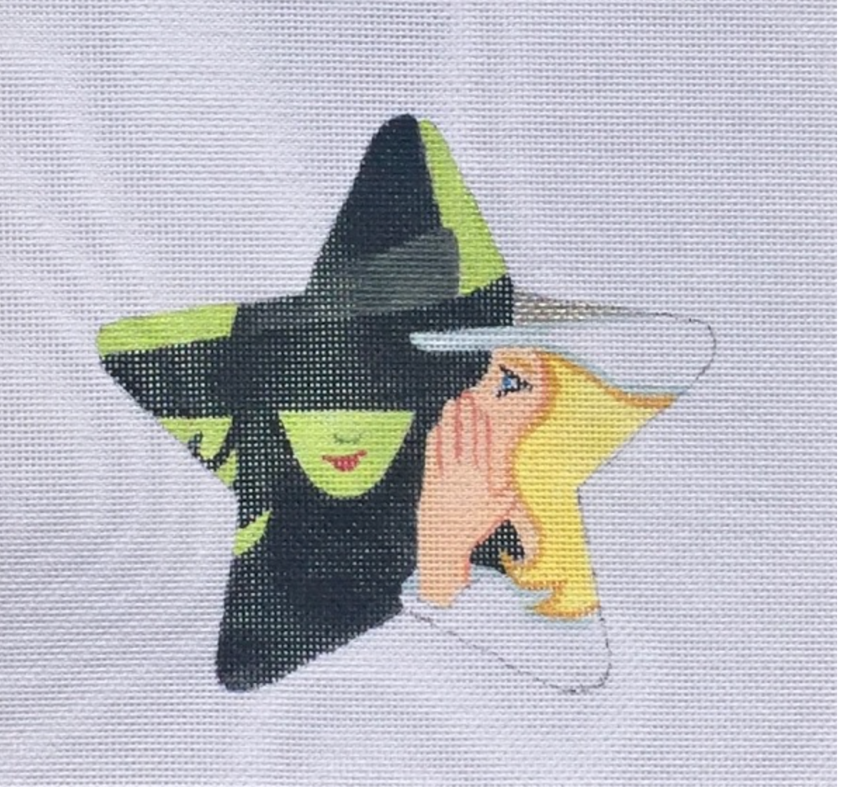 Witch and yellow-haired figure on a star-shaped needlepoint canvas.