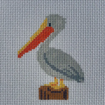 Gray pelican with red and yellow beak perched on brown log