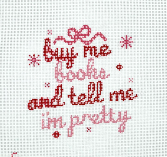 Cross-stitch design with “Buy me books and tell me i'm pretty” phrase in red and pink