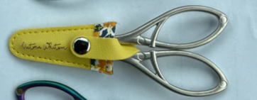Scissors with a yellow sheath featuring a brand logo 