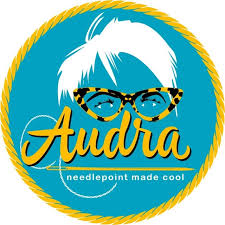Logo of Audra needlepoint with a stylized face wearing glasses on a blue background